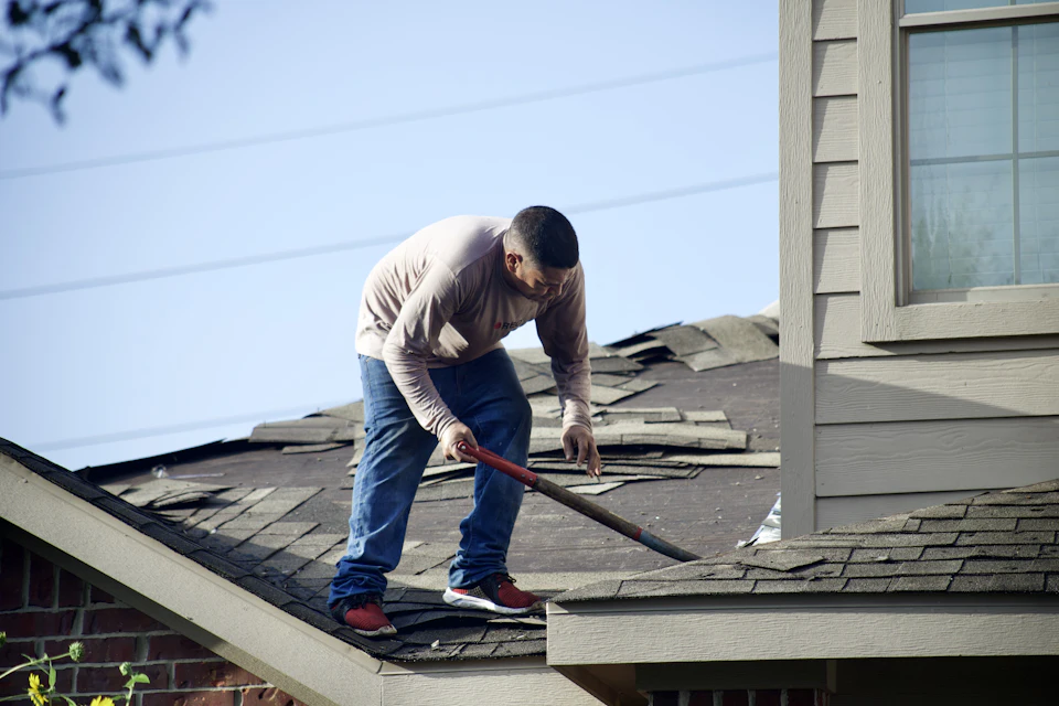 Handyman on a sloped roof clearing and repairing a gutter line