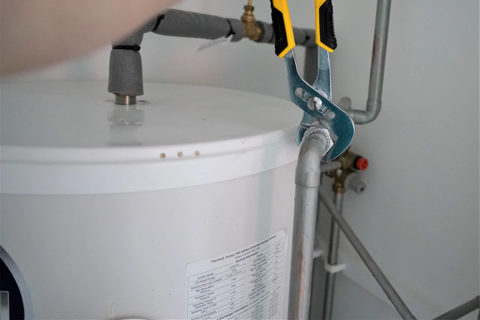 Wrench tightening a supply line above a water heater